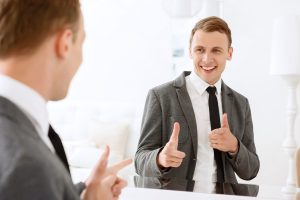 A businessman giving himself a pep talk in the mirror.