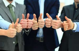 Close up of business people giving thumbs up.