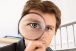 A businessman looking through a magnifying glass.