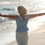 A woman at the beach with arms outstretched