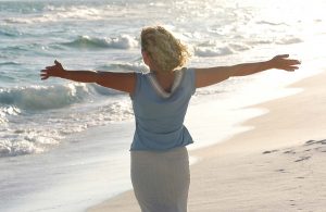 A woman at the beach with arms outstretched