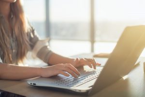 A woman at a laptop in the morning light.