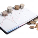Stacks of coins on a notebook with red and black graph lines