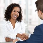 Client and writer shake hands, smiling, with respect