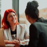 Two women wearing professional attire meet together