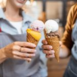 Two people "toasting" their double-scoop waffle cones