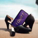 Pair of black women's shoes on the beach with cell phone message "I Quit"