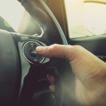 Driver's right hand pressing to adaptive cruise control button on steering wheel of a car