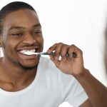 Smiling man brushing his teeth