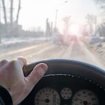 man's hand on the steering wheel of a car, dangerous road