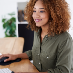Smiling woman sitting at computer sends emails to prospective clients