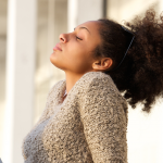 Woman faces the sun, eyes closed, face relaxed, head back