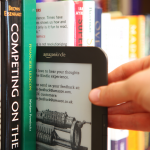 Amazon Kindle open to feedback page being tucked between hardback books on a shelf