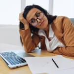 Woman at her desk looks bored at the computer screen