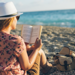 relaxed woman reads her book on the beach in peace... she's getting paid on this vacation!