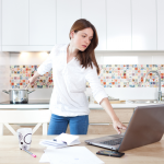 women types at computer while stirring pot on stove