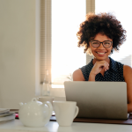 confident woman smiles from across her laptop