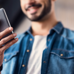 Ideal customer smiles he watches YouTube videos on his mobile phone