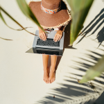 A writer relaxes on a beach with her laptop