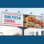 a Dominos Pizza billboard reading "Our Pizza Sucks"