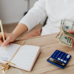 professional writer makes notes in a journal with cash in hand, calculator on the table