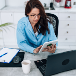 woman used a tablet to check her LinkedIn while sitting at her laptop