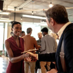 smiling woman shakes hands at a local networking event