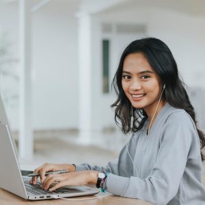 Woman at laptop smiles toward the viewer