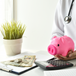 Doctor with stethoscope holds a piggy bank near a stack of papers, cash, and coins