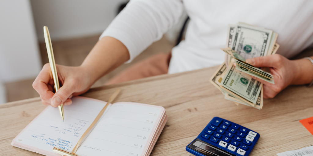 professional writer makes notes in a journal with cash in hand, calculator on the table