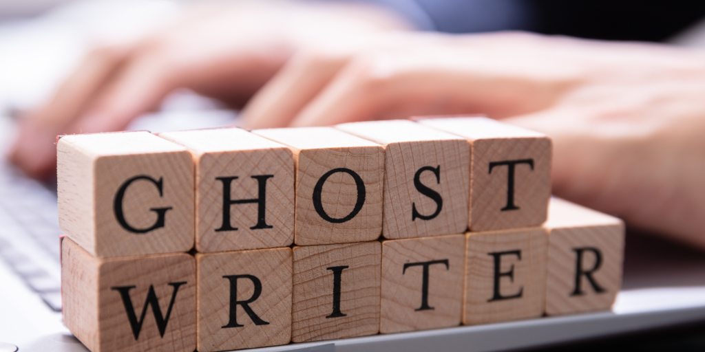 wooden blocks spell out "GHOST WRITER" next to a computer keyboard