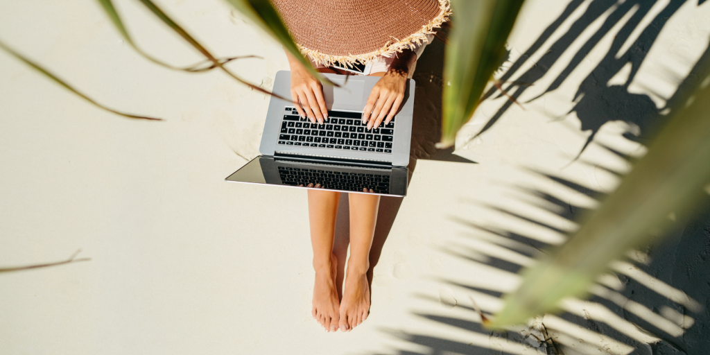 A writer relaxes on a beach with her laptop