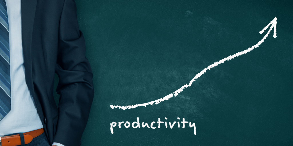 Businessman stands by a chalkboard that reads "productivity" and has an arrow going up