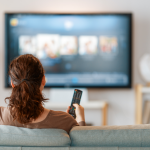 woman watches TV with bookshelf nearby